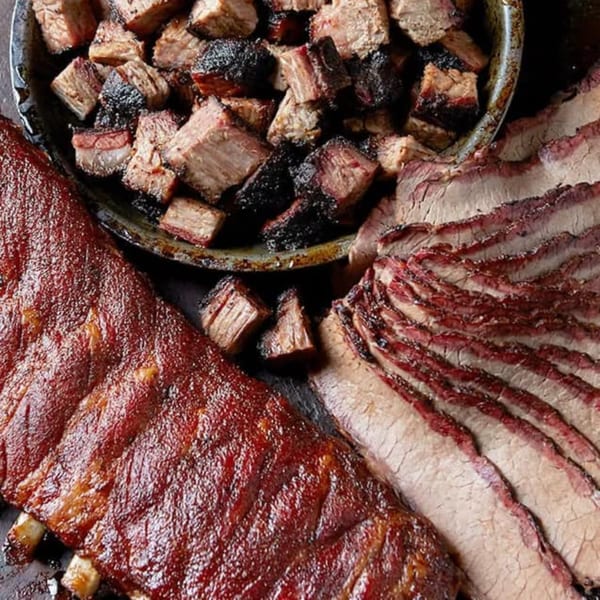 Close-up of Rep's Place BBQ ribs, sliced brisket, and burnt ends in a pan.