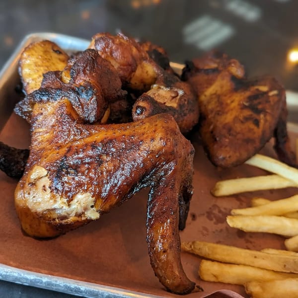 Rep's Place's crispy, dark brown chicken wings and golden french fries on a metal tray.