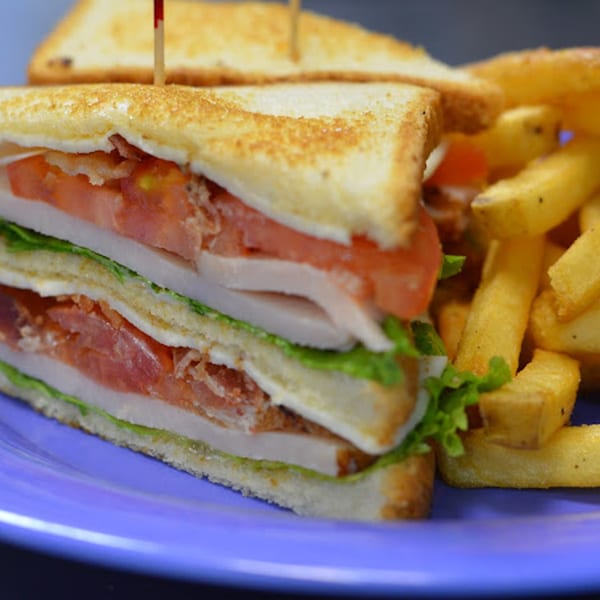 A Rep's Place club sandwich with turkey, bacon, lettuce, and tomato, served with fries.